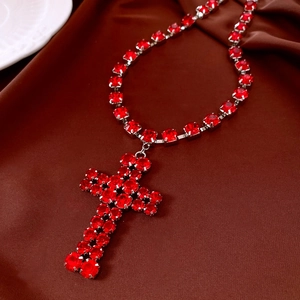 Detailed close-up of a large red rhinestone cross pendant on a matching tennis chain necklace