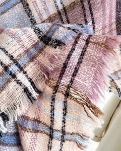 Close-up of soft plaid scarf fabric showing tassel details in pink and blue tones