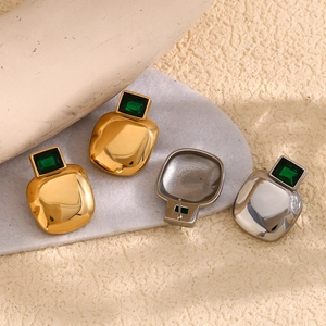 Macro detail of geometric square 18K gold plated earrings with emerald green gemstones