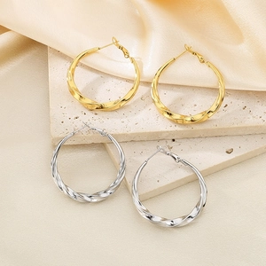 Detailed shot of twisted C-shape stainless steel earrings in gold and silver finish