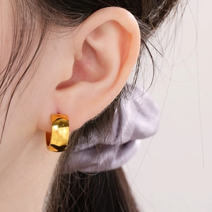 Detailed close-up of a wide 18K gold-plated stainless steel hoop earring on a model