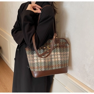 Detail of vintage plaid tote bag with brown leather straps and gold metal buckle