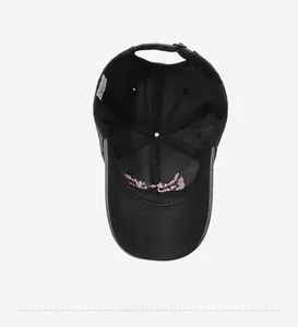 Detail of black cotton baseball cap interior featuring pink embroidery and a white care label