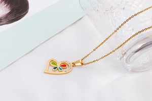 Macro view of a gold hollow heart pendant with colorful butterfly inlay and rhinestones
