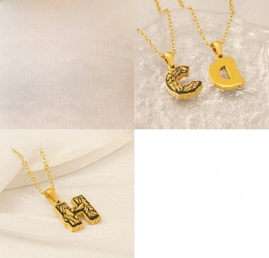 Detailed view of 18k gold plated stainless steel letter pendants with black enamel fill
