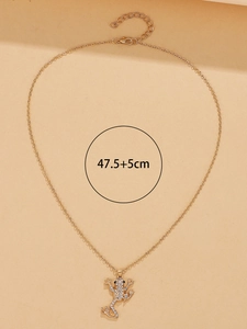 Detail of a gold frog pendant necklace encrusted with clear rhinestones on a warm beige background