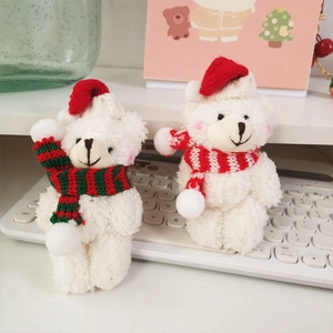 Close-up of white plush teddy bears in Christmas hats and scarves on a white keyboard
