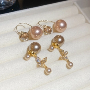 Detail of champagne gold heart and bow stud earrings with premium white pearls