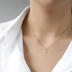 Detailed close-up of a delicate gold-plated Virgo zodiac pendant necklace on a model.