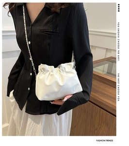 White cloud clutch bucket bag with silver chain strap worn by model against a minimalist background