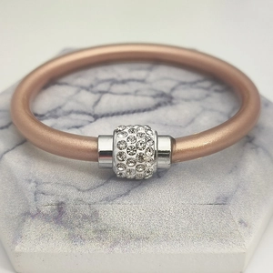 Detailaufnahme des Silikon-Lederarmbands mit kristallbesetztem Silberanhänger auf Marmorplatte