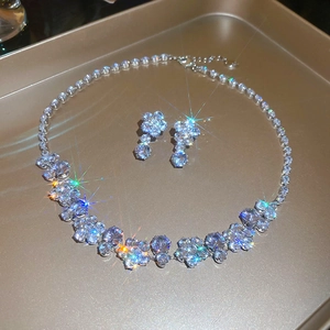 Macro shot of silver zircon flower necklace and earrings set on a golden metal tray
