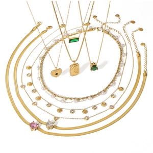 Detail of layered gold necklaces with sun moon charms, pearls and gemstone pendants