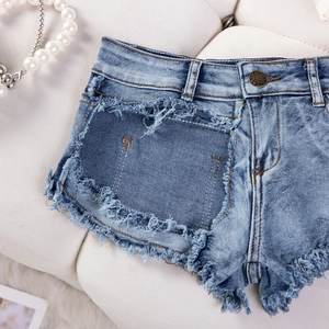 Flachbild von hellblauen Denim-Shorts mit ausgefransten Kanten und stylischen Rissen