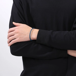 Dettaglio del bracciale in acciaio al titanio intrecciato blu al polso con trama visibile