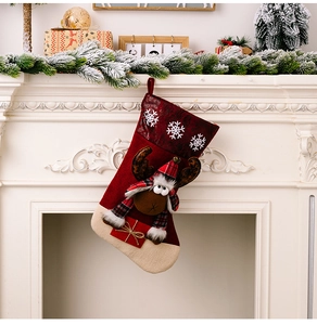 Detail of red Christmas stocking with plush elk and snowflake pattern on white fireplace