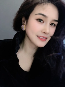 Detail of vintage 18K gold earrings with purple amber dried flowers worn by a model