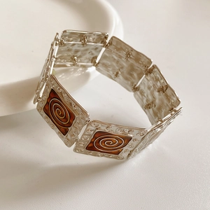 Close-up of vintage silver square bracelet with brown enamel and spiral patterns