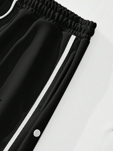 Close-up of black jogger pants featuring side stripes, elastic waist, and snap buttons