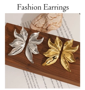 Artistic display of gold and silver leaf earrings on wood with stone and book