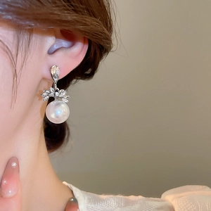Détail des boucles d'oreilles perles et strass portées sur le lobe de l'oreille