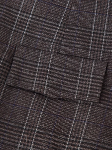 Détail du rabat de poche sur tailleur à carreaux marron montrant le tissage en tweed