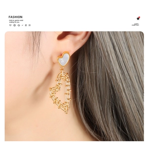 Detail of gold heart earrings featuring woven wire design and white shell inlay on model
