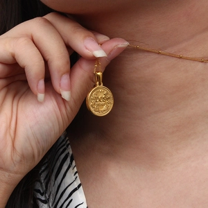 Detailed close-up of a vintage golden Dos Pesos coin pendant on a beaded link chain