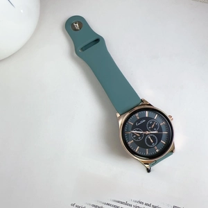 Close-up of rose gold sport watch with dark green silicone strap and crystal markers