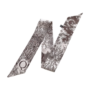 Detailed macro view of silk twilly scarf featuring capital letter Q and Toile de Jouy pattern