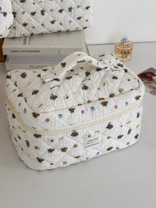 Detailed view of white quilted bread dog makeup bag with top handle and zipper closure