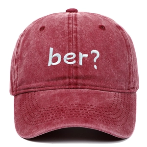 Close-up of vintage washed red baseball cap featuring blue 'ber?' embroidery and stitching