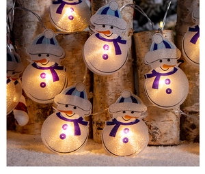 Gros plan sur la guirlande LED bonshommes de neige avec lumière chaude sur bois de bouleau