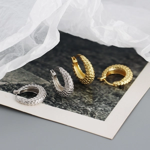 Detailed macro view of S925 silver and gold bubble-textured french hoop earrings