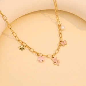 Macro detail of gold necklace with pink tulips, butterflies, flowers and a white pearl