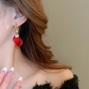 Detailed view of red frosted petal tassel earrings worn by a model in warm lighting