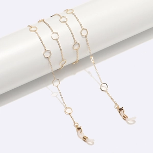 Golden floral metal glasses chain featuring cutout hexagon charms on white display stand