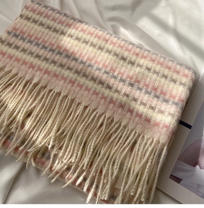 Detail of soft knit texture and long fringe on rainbow plaid winter scarf