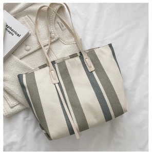 Vertical striped canvas tote bag in beige and green styled with knitwear and a book