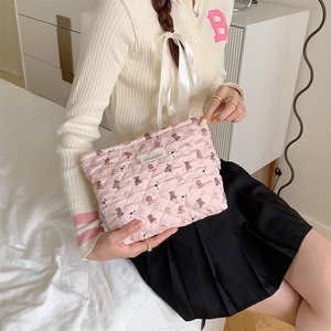 Detailed macro view of pink quilted fabric makeup bag with cute bear pattern print