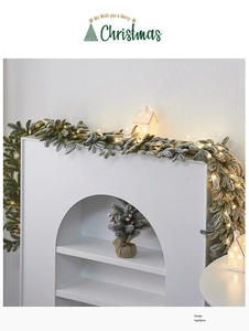 Ghirlanda natalizia innevata con luci LED su camino bianco e case di ceramica