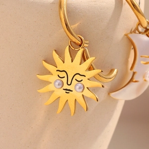Macro shot of 18K gold plated sun and moon earrings with pearl accents on stainless steel