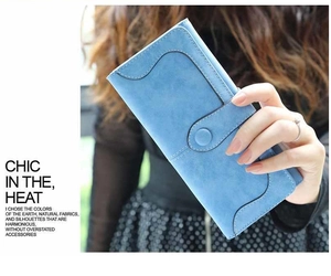 Modelo sosteniendo una cartera larga azul mate con hebilla redonda y textura de gamuza