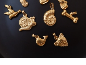 Detailed overhead shot of 18K gold-plated animal pendants on a sleek black backdrop