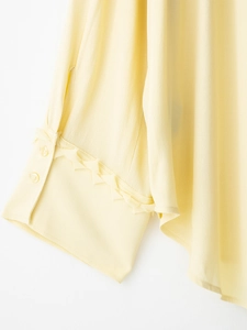 Detailed close-up of buttoned cuff and 3D floral ruffle trim on light yellow chiffon blouse