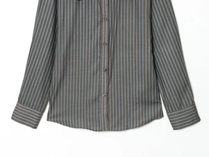 Détail de l'ourlet courbé et des boutons en résine sur cette chemise rayée