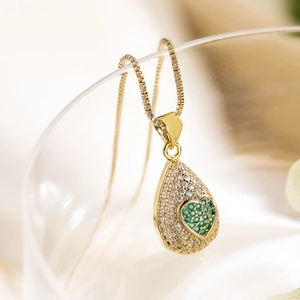 Close-up of 18K gold teardrop pendant with green heart zircon on a delicate box chain