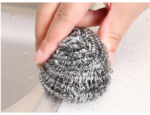 Close-up of hand using a stainless steel wire ball scrubber for kitchen cleaning