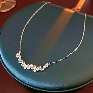 Detail of silver wheat ear necklace with sparkling zircons on green display stand