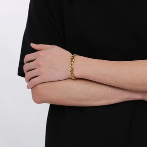 Close-up of a polished gold-plated Cuban link chain bracelet worn on a male wrist